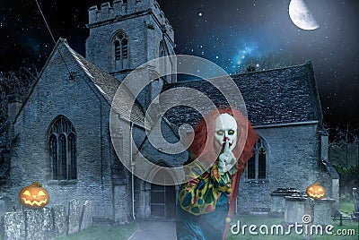 Scary halloween clown in front of an old church at night Stock Photo