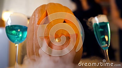 Scary Halloween pumpkin and smoky blue cocktails on party table, traditions Stock Photo