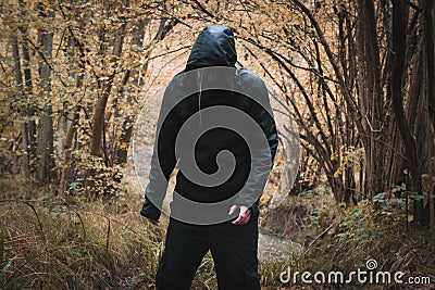 A scary hooded man wearing a plague doctor mask, standing in a forest Stock Photo