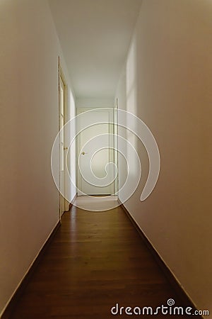 Scary light-walled hallway with a closed door illuminated by the dim shadow of a window, copy space Stock Photo
