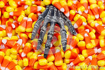 Scary skeleton hand coming out of pile of candy corn Stock Photo