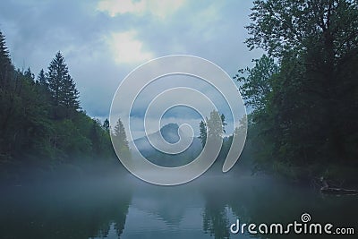 Scary spooky river of Kolpa on a gray dull summer day with clouds and overcast sky with thick fog above the water surface. Scary Stock Photo