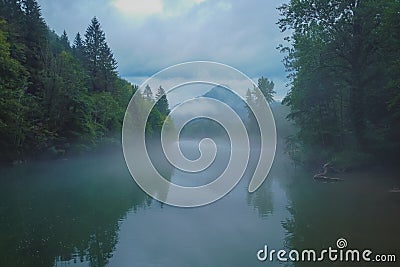 Scary spooky river of Kolpa on a gray dull summer day with clouds and overcast sky with thick fog above the water surface. Scary Stock Photo