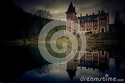 Scary view of a castle with a lake and reflection in the forest Stock Photo