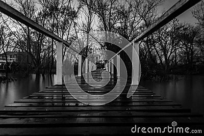 Scary view from the dock of an abandoned lake house surrounded by the contour of creepy trees Stock Photo