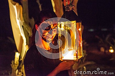 Scary woman witch with lantern and face pant during Halloween party at the artificial cemetery on the beach Editorial Stock Photo