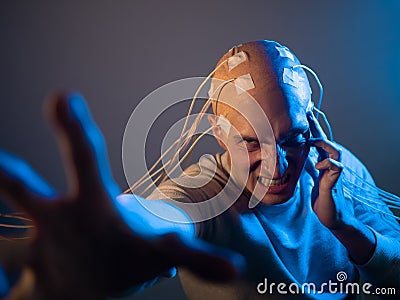 A scary young man with his head entangled in wires, uses mind control Stock Photo