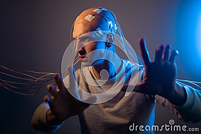 A scary young man with his head entangled in wires, uses mind control Stock Photo