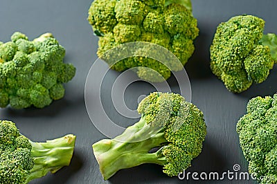 Scattered fresh bunches of broccoli on scratched dark concrete desk Stock Photo