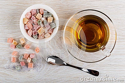 Scattered rakhat-lukum, bowl with rakhat-lukum, cup of tea on saucer, teaspoon on table Stock Photo