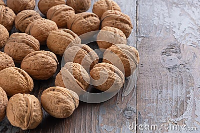 A scattering of beautiful ripe walnuts in unopened shells on a vintage wooden background. Stock Photo