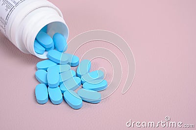 Scattering blue pills from bottle on pink background top view Stock Photo