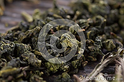 A scattering of green tea leaves on a wooden background, macro Stock Photo