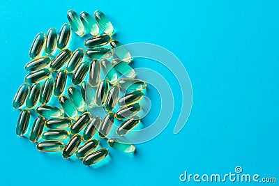 a scattering of yellow transparent fish oil capsules on a blue background,virus Stock Photo