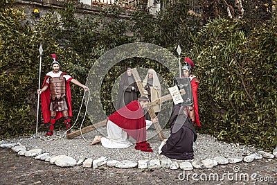 Scene of Jesus life. Unidentified man portraying Jesus Christ carries large wooden cross during reenactment of the Crucifixion Editorial Stock Photo