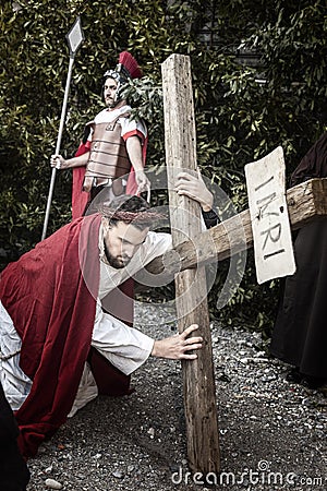 Scene of Jesus life. Unidentified man portraying Jesus Christ carries large wooden cross during reenactment of the Crucifixion Editorial Stock Photo