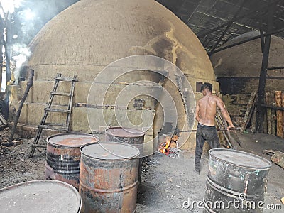 Scene of the worker putting mangrove logs into the charcoal kiln to produce pure carbon Editorial Stock Photo