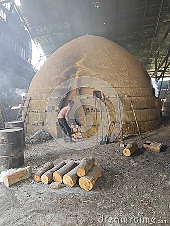 Scene of the worker putting mangrove logs into the charcoal kiln to produce pure carbon Editorial Stock Photo