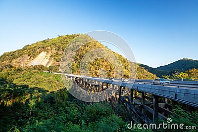 Scenery of the bear mountains bridge at dusk, golden sunset shines on the cars driving across the bridge and mountain range Stock Photo