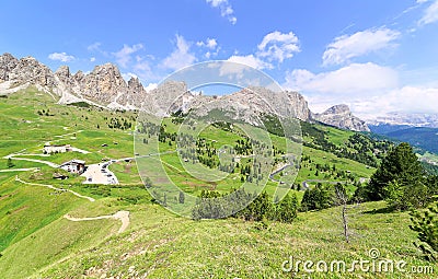 Scenery of majestic Gardena Pass on a sunny summer day with highways & hiking trails winding thru a green grassy Alpine valley Stock Photo