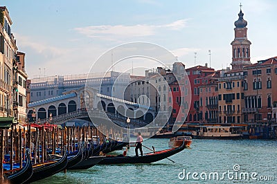 Scenery of romantic Venice before sunset, with view of a gondolier steering his ferry gondola by a pier, the famous landmark Editorial Stock Photo