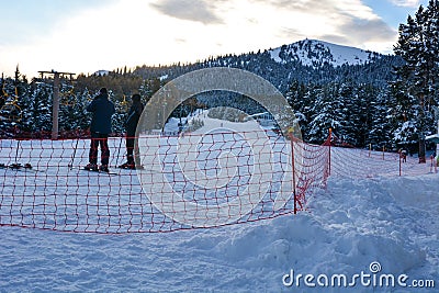 Scenic alpine landscape with two skiers waiting for ride in Karakol ski resort. Stock Photo
