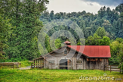 A scenic barn surrounded by trees and flowers Stock Photo