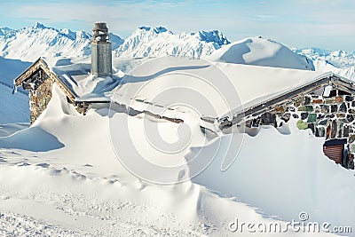 Scenic Highland alpine old abandoned stone hut with chimney snowbound by thick snow layer after blizzard. Mountain rustic shelter Stock Photo