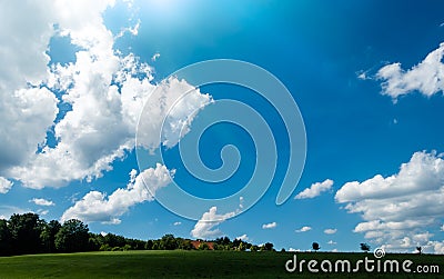 Scenic Landscape with predominant Blue Sky and Clouds over Green Forest Stock Photo