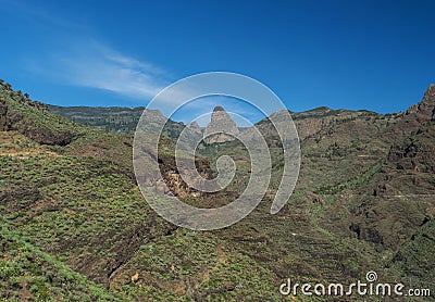 Scenic landscape with Roque de Agando rock at hiking trail through Barranco de Guarimiar Gorge. Green mountain canyon Stock Photo