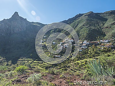 Scenic landscape with Roque de Imada rock and village at hiking trail Barranco de Guarimiar Gorge. Green mountain canyon Stock Photo