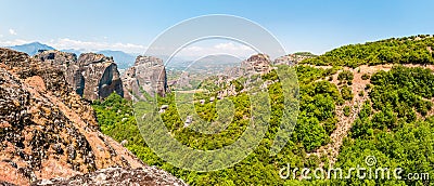 Scenic panoramic landscape view on Meteora rock formations cliffs and peaks surrounded by vibrant green plants and trees in Greece Stock Photo