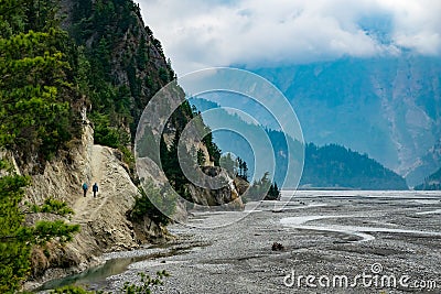 Scenic photo of two trekkers walking in the Gandaki river valley in the Annapurna Circuit, Himalayas Stock Photo