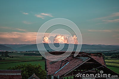 Scenic shot of a farm field with the roof of an open wooden bales storage Stock Photo