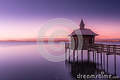 Scenic shot of a gazebo overlooking a calm lake under a gradient sky during dusk Stock Photo