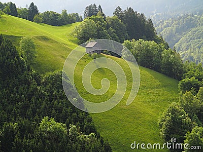 Mountain hut on steep green hill Stock Photo