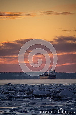 Scenic sunset over the iced St Lawrence River and a ship in Quebec, Canada Stock Photo