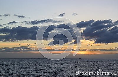 Scenic sunset over the sea. The sun sets on the water. Clouded sky is painted with bright colors. Sunset beach in a summer evening Stock Photo