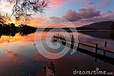 Scenic sunset and reflections on lake with old jetty Stock Photo