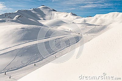 Scenic valley of hilghland alpine mountain winter resort on bright sunny day. Wintersport scene with people enjoy skiing Stock Photo