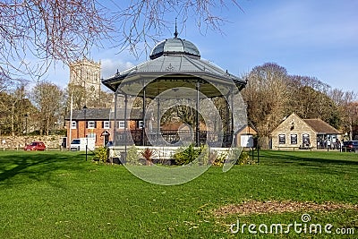 A scenic view of a bandstand in a park with a church and trees in the background under a majestic blue sky Stock Photo