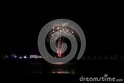 A scenic view of a majestic multicolor firework with reflection over the water under a majestic black sky Stock Photo