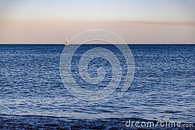 Scenic view of a sailboat gliding across a tranquil sea at sunset Stock Photo