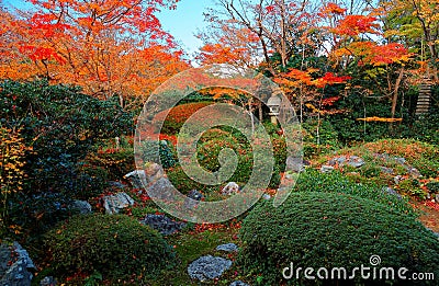 Scenic view of a stone lantern under fiery maple trees in the beautiful garden of Genkoan Stock Photo