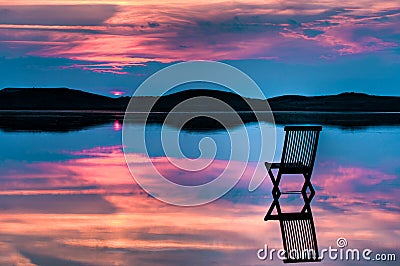 Scenic view of sunset with chair in calm water Stock Photo