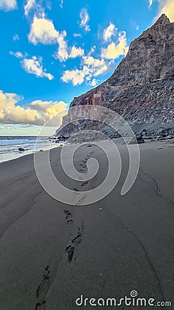Scenic view during sunset on the volcanic sand beach Playa del Ingles in Valle Gran Rey, La Gomera. Footprint in sand Stock Photo