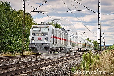 Scenic view of a train moving along the railway tracks surrounded by a lush green landscape Editorial Stock Photo