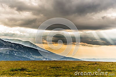 Scenic view of the Transalpina road with the sunshine peeking through clouds, Romania Stock Photo