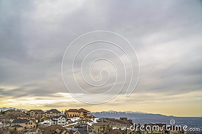 Scenic winter view of houses on a snowy mountain against cloudy sky at sunset Stock Photo