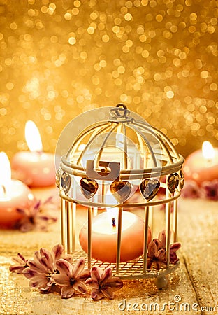 Scented candle in vintage birdcage. Golden background Stock Photo